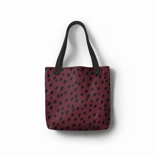 Front view of TASHAU tote bag in burgundy with abstract black dot pattern.