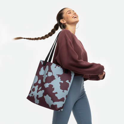 Woman holding the Cenote Depths tote bag with maroon and sky-blue abstract design by TASHAU.